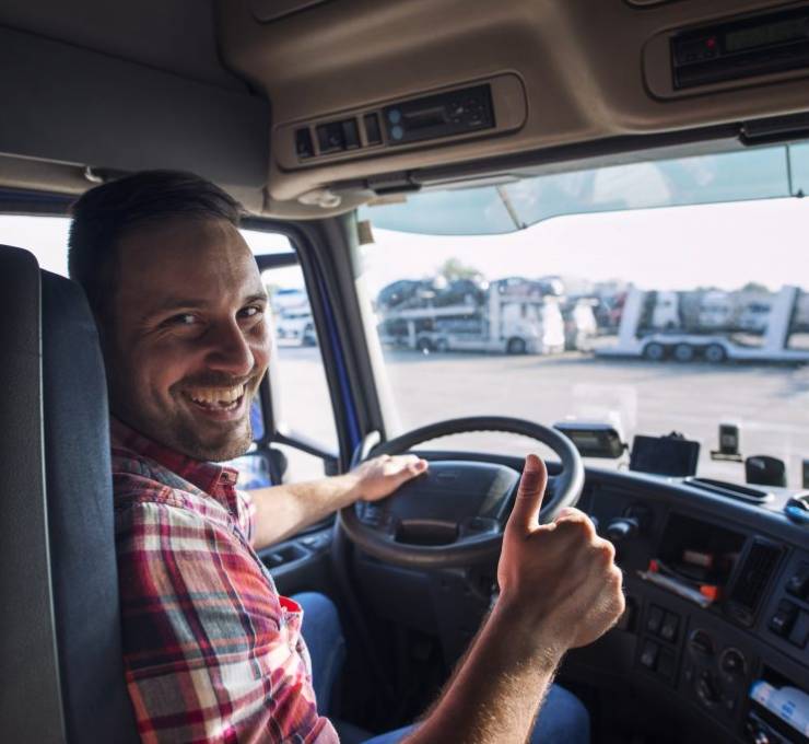 portrait-truck-driver-sitting-his-truck-holding-thumbs-up-1024x683
