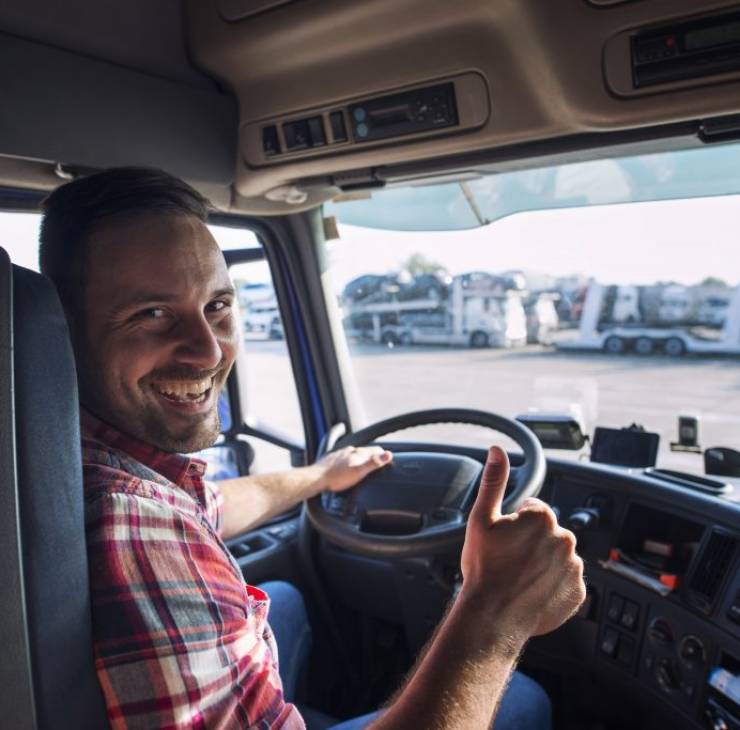 portrait-truck-driver-sitting-his-truck-holding-thumbs-up-1024x683